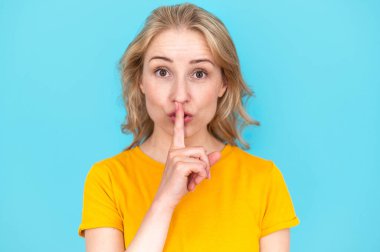 Sarı tişörtlü genç bir kadın sessiz olmak istiyor. Dudaklarında parmak var. Sessiz bir jest yapıyor. Gizli satış ve kara cuma indirim konsepti..