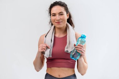 Spor motivasyonu konsepti. Genç sportif spor spor eğitmeni kadın, elinde beyaz fotokopi arka planında izole edilmiş su şişesiyle jimnastik salonunda vakit geçiriyor..