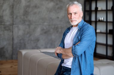 Olgun, kendine güvenen bir adamın kafasından. Erkek pozu çatı katında yalnız, kanepenin yanında dur ve kameraya bak. Profesyonel meslek, serbest portre, ev sahibi kişi kavramı