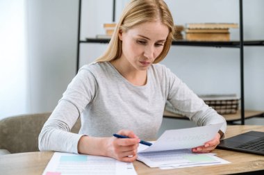 Ofiste oturan odaklanmış bir kadın, belgelere bakıyor, kağıt sözleşmesine bakıyor. İş danışmanlığı veya yönetici iş yerinde anlaşma bilgilerini okuyor.