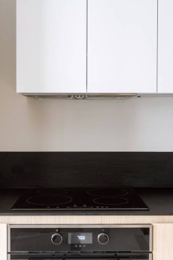 Mutfak dolabının kaputunun altında elektrikli cam seramik soba ile dikey çekim. Yeni ev aletleriyle birlikte modern iç mekan elementi.