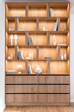 Yeni ahşap kitaplığın dikey ön çekimi, dergi koleksiyonları, kütüphane dolabındaki raflarda okumak için kitaplar. Oturma odası için açık alan ve çekmeceleri olan mobilya tasarımı