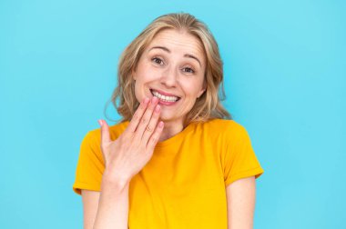 Woman with oops reaction isolated on blue background. Making mistake, fail, sorry. Happy and funny female overwhelmed by fake news, drama or secret with regret, shame or awkward clipart