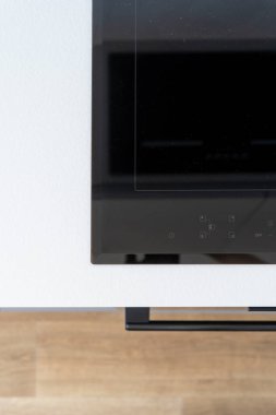 Düz siyah cam manzarası, beyaz ahşap tezgahta kontrol paneli olan seramik indüksiyon hob. Modern mutfaktaki ev aletleri. Yemek pişirmek için elektrikli ocak. Reklam kavramı