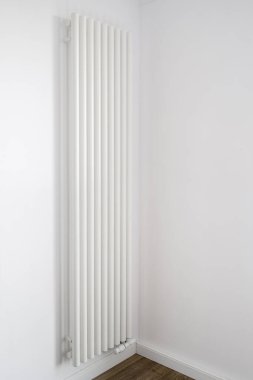 Dikey radyatör, boş odada, minimalist iç tasarımla birlikte beyaz duvara kurulur. Modern merkezi ısıtma sistemi olan ev ya da daire. Konforlu yaşam için kaynakların sorumlu tüketimi