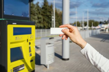 Bulanık ATM, otobüs durağı toplu taşıma geçmişine karşı kadınların elindeki kağıt bilete odaklan. Uzayı kopyala Seyahat kartı gösteren kadın.