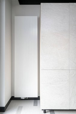 Beyaz büyük radyatör teçhizatının dikey görüntüsü apartmandaki gardırobun yanındaki duvara yerleştirildi. Evdeki merkezi ısıtma sistemi. Modern teknoloji kavramları. Mekanik basınç kontrolü.