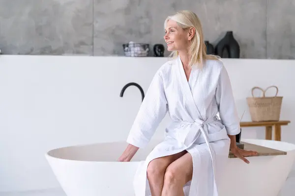 Ruhige Frau Mittleren Alters Sitzt Auf Dem Rand Der Badewanne lizenzfreie Stockfotos