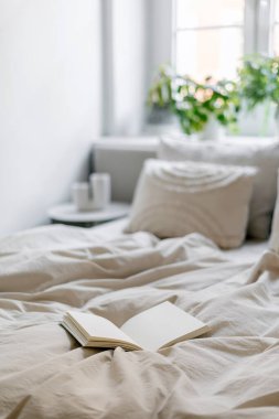 Açık kâğıt defter üzerine seçici bir şekilde odaklan. İçinde boş sayfalar, battaniyeli yataklar ve modern ışıklandırmalı yatak odasındaki yastıklar olsun. Sabahları otel odasında kırışık yatak günlüğü.