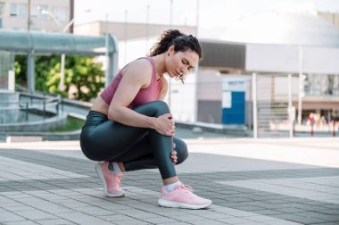 Genç sportif kadının bacağında kas ağrısı ya da kramp var. Koştuktan sonra kaza, açık havada eğitim. Spor giyimli bir kadın incik kemiğinde sakat bir nokta tutuyor.