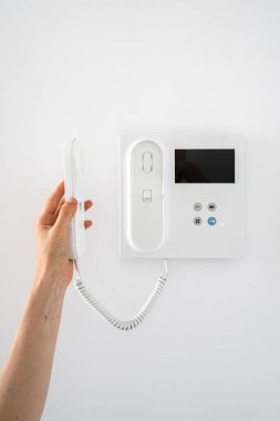 Kadının dikey görüntüsü telefonu kaldırır, misafir zili çalarken çağrıya cevap verir. Güvenlik kontrolü kullanan bir kadın, apartmanın ön kapısını açıyor. Evdeki akıllı gözetleme sistemi