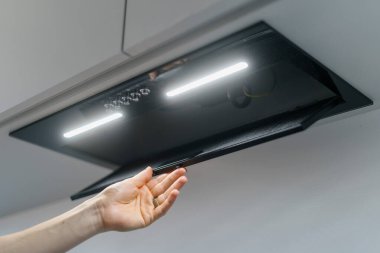 Metal kaput sökücüsünden kesilen kadının el değiştiren alüminyum ağ filtresinin düşük açısı. Bakım evi aletleri kavramı, modern mutfağın beyaz duvar arka planı.