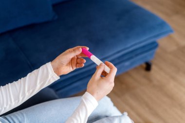 Başarılı yapay döllenme sonuçları doğrulandı. Ivf kavramları. Yüksek açı, kadın eli ve hamilelik testi görüntüsü. Kadın gebelikle ilgili iyi haberlerle karşılaşıyor.