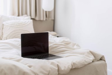 Çift kişilik yatakta, yastıklı dizüstü bilgisayarı aç. Yatak odasında, içi aydınlık çarşaflar olsun. Rahat otel odasında bilgisayarla dinlen. Modern teknoloji. Serbest Çalışan, Çalışan veya Çalışan Konsepti.