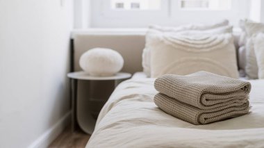 Modern ışıklandırmalı otel odasındaki temiz banyo havluları, yastıklı rahat çift kişilik komodinli yatak, çarşaf ve battaniye örtüsü.