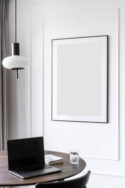 Masada modern dizüstü bilgisayarın dikey görüntüsü var. Minimalist tarzda. Boş bilgisayar görüntüsü duvar dekoruna karşı dairede fotokopi çerçevesi ile. Uzaktan çalışma, ev ofisi, online eğitim kavramları