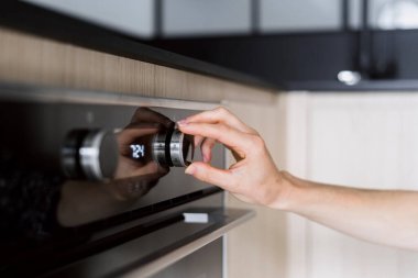 Kadın el düzenleme düğmesini kapat, mikrodalga modunu dijital ekran ve kontrol panelinde düğmeleri olan modern fırında seç. Ev hanımı mutfakta yemek pişirirken ev aletlerini kullanıyor.