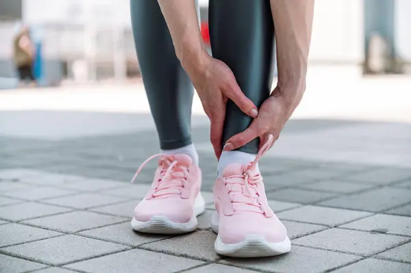 stock image Ankle pain. Selective focus on woman hands touching painful point on leg after running outside. Sprains, strains, fracture, tendonitis. Health problems concept . Sports injury.