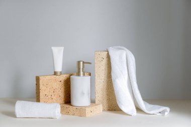 Zarif kozmetik ürünleri setiyle hala yaşam kompozisyonu. Deri bakımı için ambalaja yakın ellerde sıvı sabun bulunan mermer şeker şişesi. Temiz beyaz havlunun yanında lüks yüz kremi.