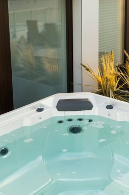 Hidromasaj jeti olan jakuzi. Arka bahçedeki terasta filtrelenmiş temiz mavi suyu olan jakuzi. Otel kompleksi, spa tedavisi, refah ve eğlence kavramları