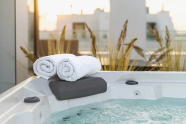 Köşesinde havlu olan jakuzi. Turizm merkezinde hijyen, güzellik ve kaplıca tedavisi. Otel servisi, sağlık, hidroterapi konsepti. Çatıda jakuzi var. Yüzme havuzlu açık teras