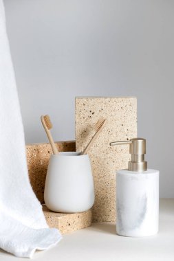 Sabah rutini, diş bakımı, ağız bakımı ve hijyen kavramları. Diş fırçası tutacağı, yanında ahşap çevre dostu fırça sabun şişesi ve hafif banyoda havlu.