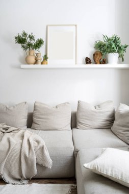 Yastıklı ve ekoseli rahat kanepe, dallı vazo, saksı yeşili bitki, heykelcik ve resim çerçevede, oturma odasındaki duvar rafında ışık tonlu İskandinav iç dekorasyonu ile birlikte fotokopi odası