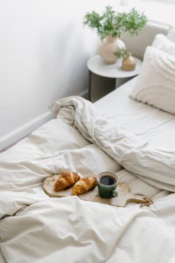 Tahta tahtada yüksek açılı manzara, yatak odasındaki yumuşak battaniyenin yanında kahvaltı. İçerisi aydınlık, otel odasında taze fırınlı sabah kahvesi. Eğlence anlayışı.