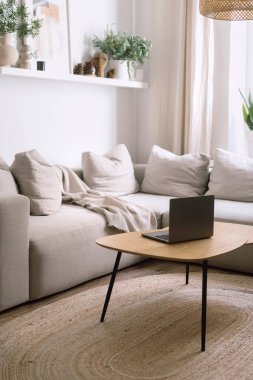 Oturma odasında, içinde defter olan bir sehpa ve yastıklı rahat bir kanepe olan parlak etnik tarzda dikey bir sahne. Rattan halısı yerde. Çalışmak ve çalışmak için rahat bir yer.
