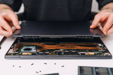 Tamirci dizüstü bilgisayarı tutar, kapağı açar ve cihaz bileşenlerini kontrol eder. Hizmetteki ya da garanti merkezindeki hasarlı aküyü değiştirin. Dijital tablet veya dizüstü bilgisayarın içerisindeki elementlere seçici odaklanma