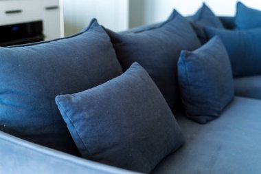 Oturma odasındaki modern koltuktaki mavi yastığa odaklan. Koltukta kadife kumaş. Yumuşak modüler mobilyalarda döşeme kavramı