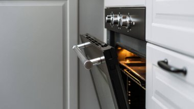 Modern elektrikli fırının metal sapıyla açılan siyah kapıya odaklan. Evde yemek pişirmek. Ev aletleri, fırın ekipmanı konseptiyle yapılmış mutfak.