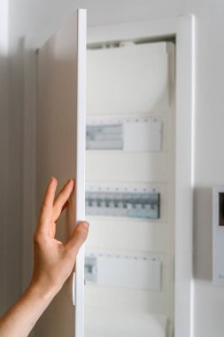Ev elektrikli kalkanındaki kontrol panelinin metal kapısını açan kadına odaklan. Devre kesicili voltaj dağıtıcısına erişim.