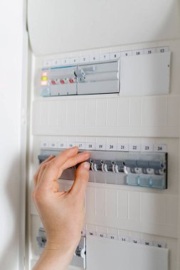 Kadın elinin elektrik panelindeki düğmeyi açmasına odaklan. Dolabın içinde kadın şalter değiştiriyor. Evde voltaj dağıtıcısı var.