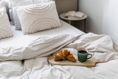 Kahvaltı tepsisine odaklan. Bardaklı ve fırınlı. Rahat, yumuşak yatak odasındaki. Modern evde içi aydınlık bir oda.