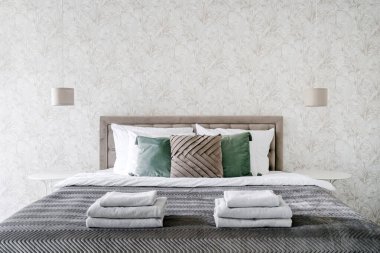 Klasik otel süitinde çift kişilik yatak üzerine yığılmış beyaz havlular. Şık yatak odalı bir dairede iç dizayn. Pamuk tekstil ile konuklar için yer