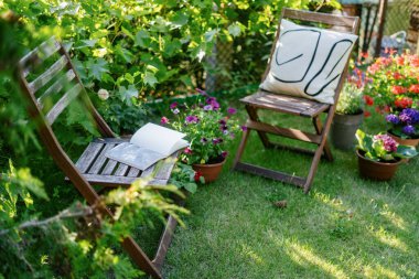 Yaz bahçesi. Bir kitap ve dekoratif yastıklı iki tahta sandalye çimenli bir çimenlikte çiçeklerle çevrili olarak otururlar. Gölgeli arka bahçedeki eğlence alanı. Okuma ve dinlenme zamanı.