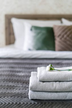 Üstünde çiçek olan temiz ve taze havlulara seçici bir şekilde odaklan. Yatak odasının içerisine sahip otel servisi kavramları. Turist dinlenme odasında rahat bir yatak.
