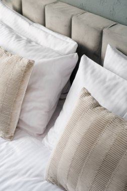 Temiz çarşaflardan, beyaz yastık kılıflarında hipoalerjenik yastıklardan ve yumuşak dekoratif yastıklardan oluşan rahat bir otel yatağı. Rahat yatak odasındaki uyuma alanını kapat