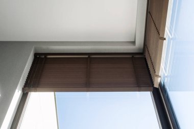 Ahşap panjurlu geniş panoramik pencerenin düşük açılı görüntüsü yayılmış ışığın odanın içine girmesine izin veriyor. Modern ev, konut binası, dekor ve tasarım kavramları