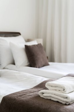 Oteldeki ikiz odada, rahat yatağın üstünde temiz banyo havluları var, dikey çekim. Otel servisi kavramları. Misafir odalı rahat bir dairede iç mekan.