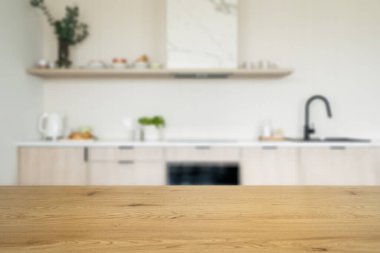 Boş mutfak masası, seçici odaklanma. Ürün gösterimi için model yüzeyi. Modern iç mekanda ahşap tezgah, kabinler, siyah musluk ve elektrikli fırın fotokopi alanına karşı bulanık arkaplan