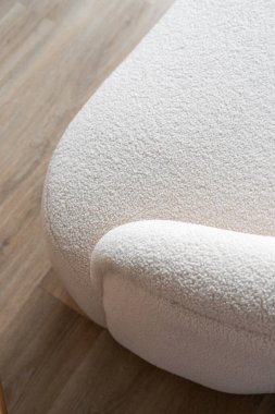 Minimalist mobilyalar ve kuru temizleme konseptleri. Beyaz pelüş kumaşlı ve desenli yüzeyi olan kanepe kolluğunun yakın çekimi. Odadaki şık ve zarif kanepenin bir parçası, yüksek açı manzaralı.