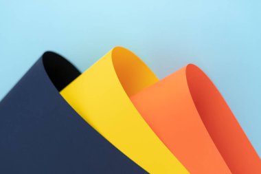 Renkli kâğıt rulo koleksiyonu mavi bir fotokopi arkaplanı, düz görünüm karşısında yatar. Origami çarşaflarının yumuşak, dalgalı kıvrımları tasarım ve yaratıcılık için sanatsal bir yetenek sergiliyor. DIY kavramları