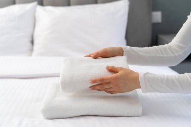 Kırpılmış kadın, yıkanmış konukları otel odasındaki yatağa koyar. Yatak odasında banyo tekstili. Temizlik, temizlik ve konforlu yaşam konseptleri
