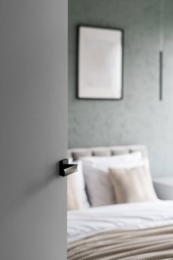 Beyaz, yatak odasının kapısını minimalist iç döşeme ile açtı. Temizlik hizmeti, konukseverlik, otelde kalma rahatlığı. Duvar dekorlu bir oda. Şablon resim çerçevesi, resim posteri