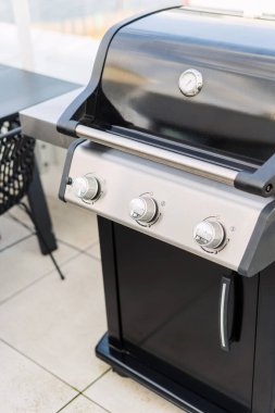 Yeni ve siyah gaz ızgarası verandada ızgaraya hazır, yüksek açılı manzaralı. Mangal malzemelerinin dikey çekimi. Açık hava mutfak aletleri kavramları