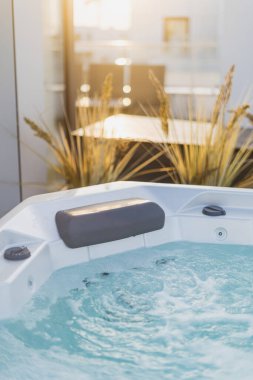 Dikey ergonomik ve konforlu başlık yastığı ve hidromasaj jetli lüks jakuzi. Arka bahçedeki terasta güneş ışığında banyo elementi. Spa kompleksi, tatil, seyahat konsepti