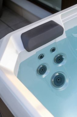 Temiz mavi suyu olan yüksek açılı jakuzi manzarası. Küvette hidromasaj jeti üzerinde rahat kafalık yakın çekim. Lüks otel tatil beldesinde spa tedavisi, eğlence ve refah kavramları