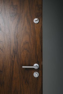 Kapalı ve ahşap ön kapının dikey görüntüsü zengin tahıl desenli, modern apartman dairesinde stil metal saplı ve kilitleri var.